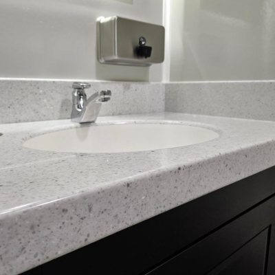 This washroom countertop showcases a stunning white quartz surface, known for its sleek finish and durability, paired with bold black cabinets for a striking, modern contrast. The luxurious quartz offers a polished, clean look, while the black cabinets provide depth and sophistication, creating a refined and elegant aesthetic perfect for any upscale event setting.