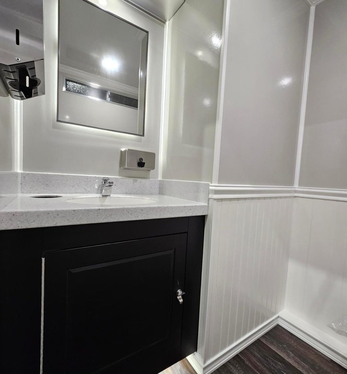 The interior of our luxury washroom trailer is a blend of modern elegance and high-quality design. The white quartz countertop contrasts beautifully with the sleek black cabinets, while the backlit mirror adds a touch of sophistication. Soft, ambient lighting enhances the space, creating a warm and inviting atmosphere that ensures your guests experience both comfort and luxury.